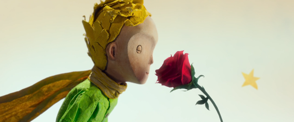 A toy child smelling a red rose